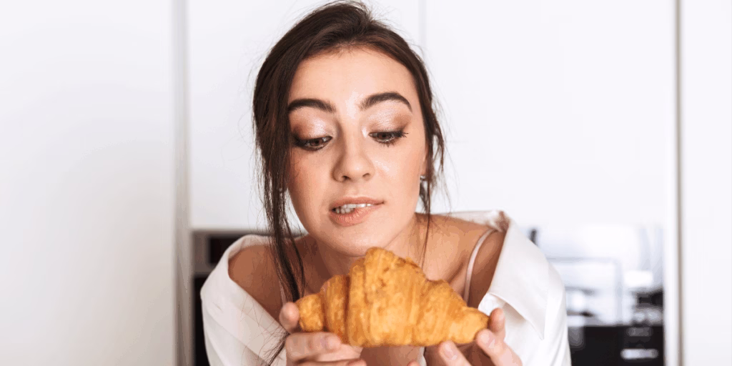 Person enjoying a fresh croissant at home, illustrating a relatable, human story for social media content.