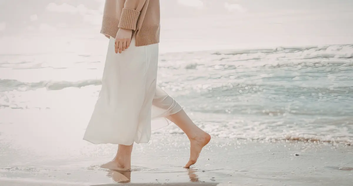 An aspirational lifestyle photograph of a person walking calmly on a beach, illustrating the freedom gained from calculating true hourly rate and delegating.